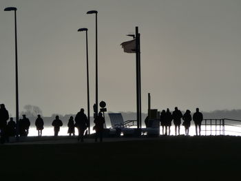 Silhouette people at street against sky