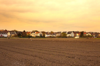 Houses on field against sky during sunset