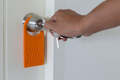 Cropped hand of woman opening door with do not disturb sign at door