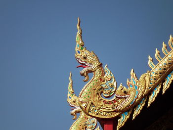 Low angle view of statue against temple against clear blue sky