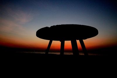 Silhouette lifeguard hut on beach against sky during sunset