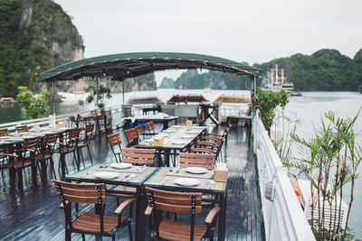 Empty chairs and table on boat at ha long bay