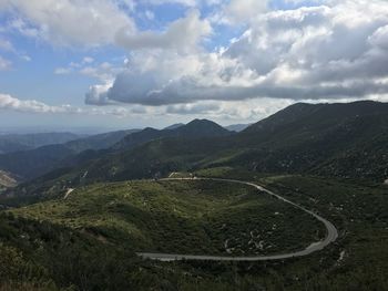 High angle view of road trail amidst mossy landscape by mountains against cloudy sky