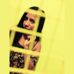 Portrait of woman holding yellow wall