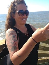 Portrait of woman wearing sunglasses at sea shore