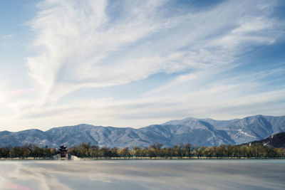 Scenic view of lake and mountains against cloudy sky