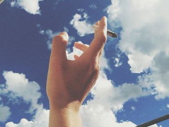 Low angle view of woman hand against sky