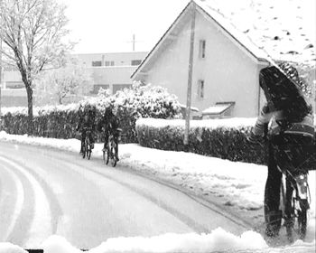 Snow covered houses and trees by buildings