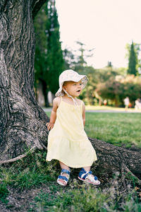 Full length of cute girl on tree trunk