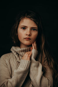 Portrait of beautiful young woman against black background