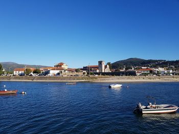 Scenic view of sea and buildings against clear blue sky