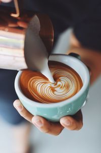 Close-up of hand holding cappuccino