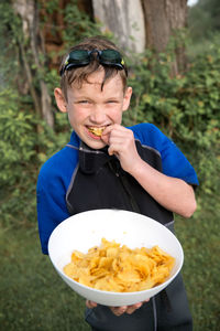 High angle portrait of boy eating potato chips on field