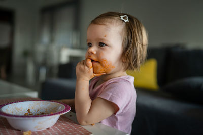 Close-up of cute girl eating food at home