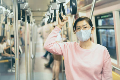 Portrait of woman wearing mask standing at subway train