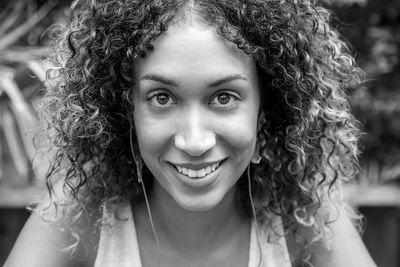 Close-up portrait of smiling young woman with curly hair