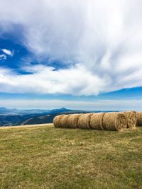 Hay bales on field against sky