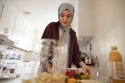 Woman in headscarf setting table for eid al-fitr at home