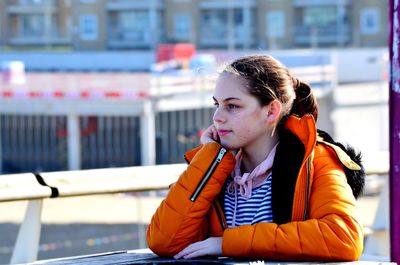 Portrait of young woman looking away while sitting in winter