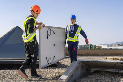 Technicians carrying solar panel at solar power station