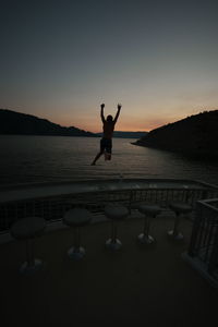 Boy jumping in sea during sunset