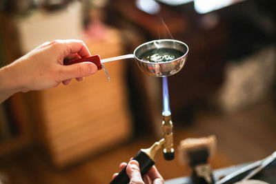 The master girl with a gas burner boils water in a ladle to relieve tension from the metal, 