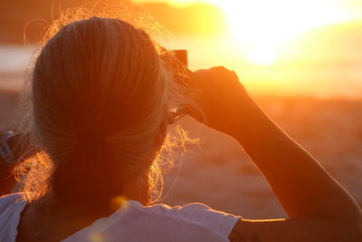 Rear view of woman against sun during sunset