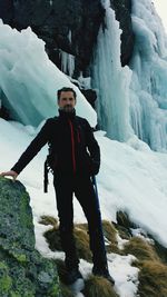 Full length portrait of mid adult man standing on snow covered mountain