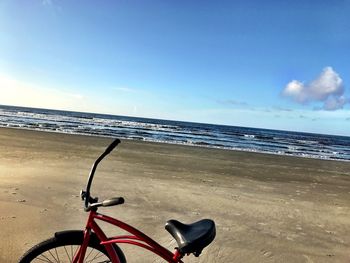 Bicycle on beach against sky