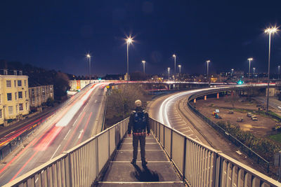 Rear view of man standing on staircase in city at night