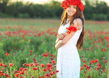 Woman holding red umbrella standing on field