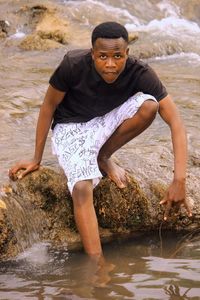 Portrait of young man standing by rock