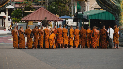 Rear view of people walking on street by buildings in city