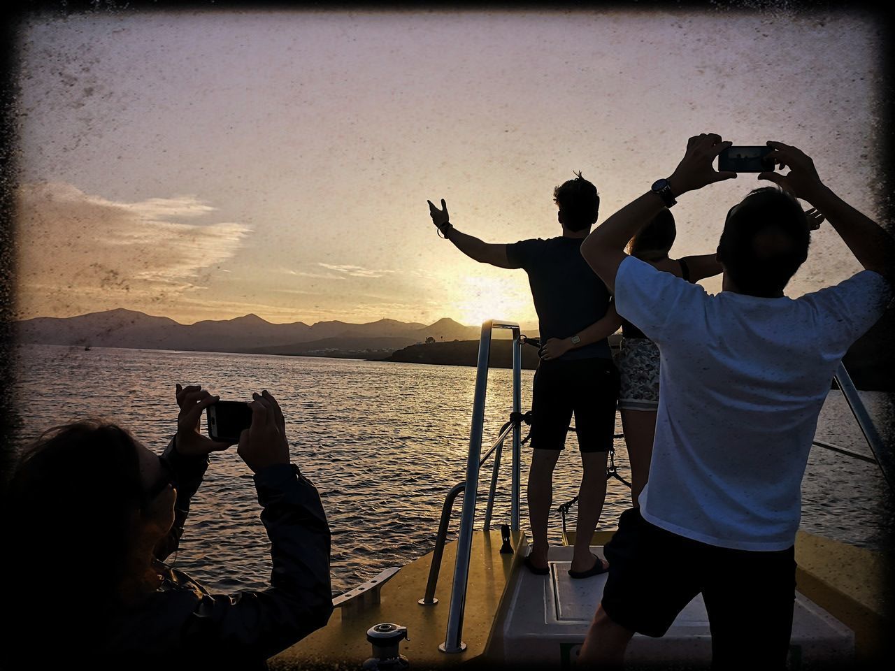 PEOPLE PHOTOGRAPHING AT SEA DURING SUNSET