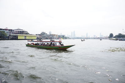 Boat sailing in sea against sky in city