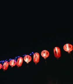 Low angle view of illuminated lanterns hanging against sky at night