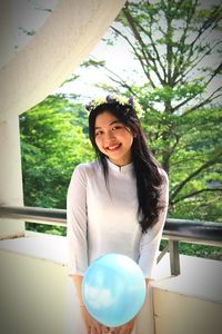 Portrait of smiling young woman standing against trees