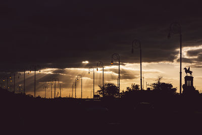 Silhouette of street against sky at sunset