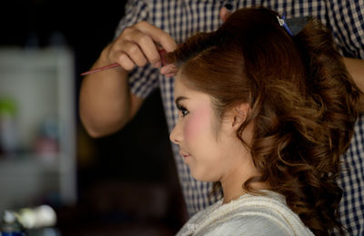 Midsection of hairdresser styling woman hair