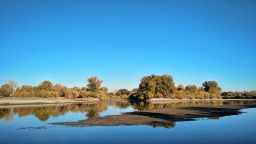 Scenic view of lake against clear blue sky