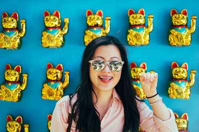 Close-up of woman wearing sunglasses against maneki neko