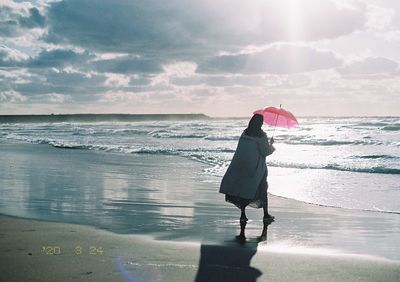 Full length of woman standing on beach against sky