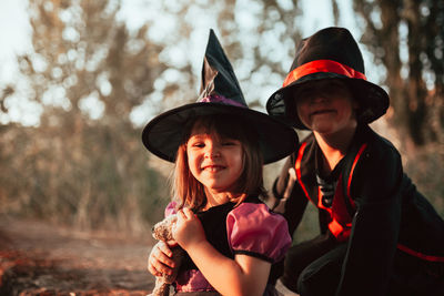 Cute siblings in costume against trees during halloween