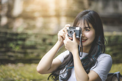 Portrait of smiling young woman holding camera