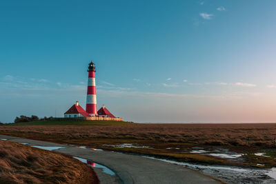 Lighthouse by sea against sky