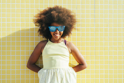 Happy girl with hands behind back wearing sunglasses