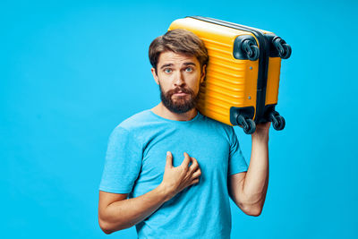 Portrait of young man standing against blue background