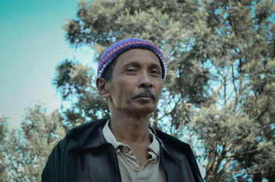 Portrait of man wearing hat against trees