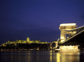 Illuminated chain bridge over river danube by buda castle against sky at dusk