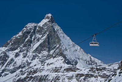 Low angle view of snowcapped mountain against blue sky